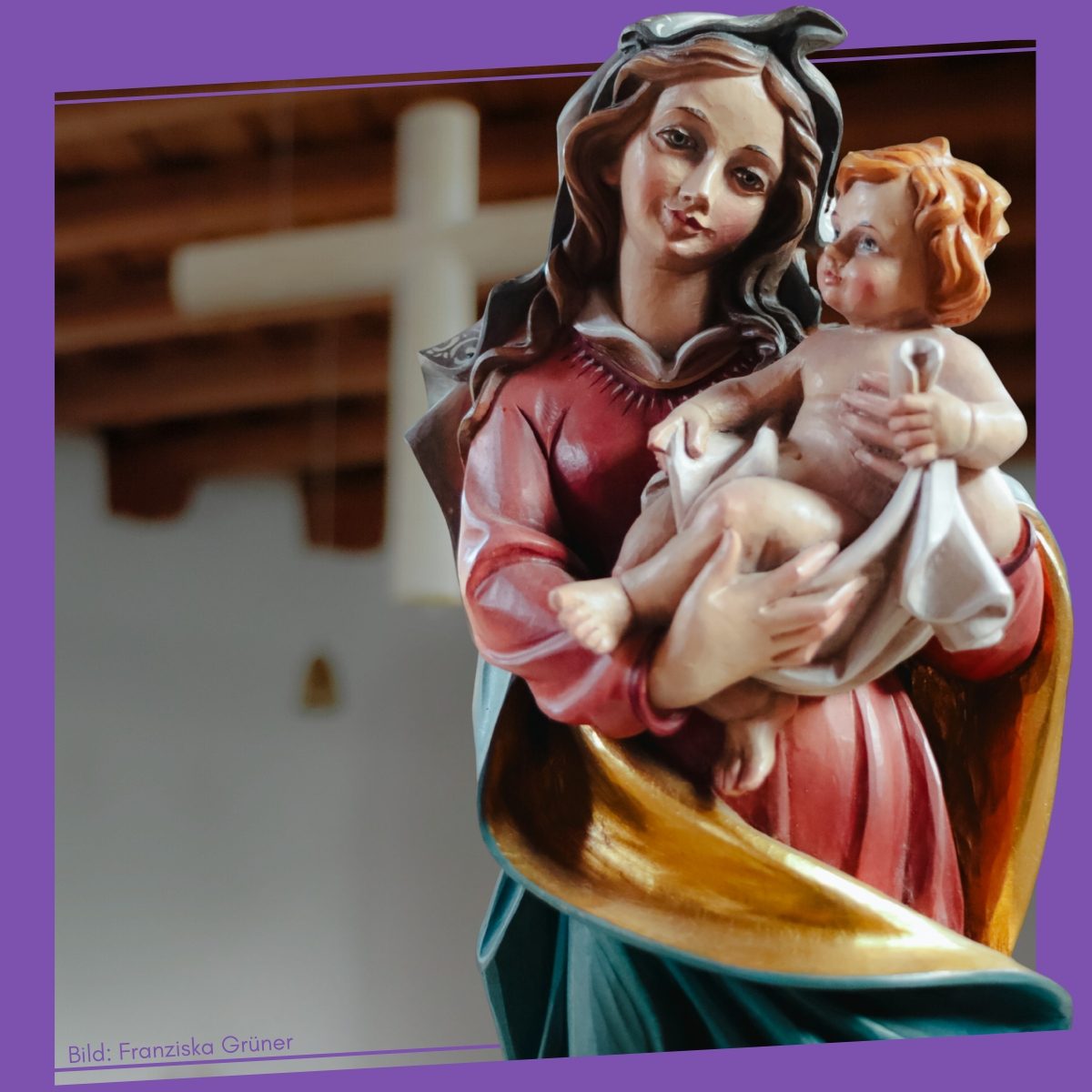 Eine Statue der Maria mit dem Jesuskind in farbenfroher Kleidung.