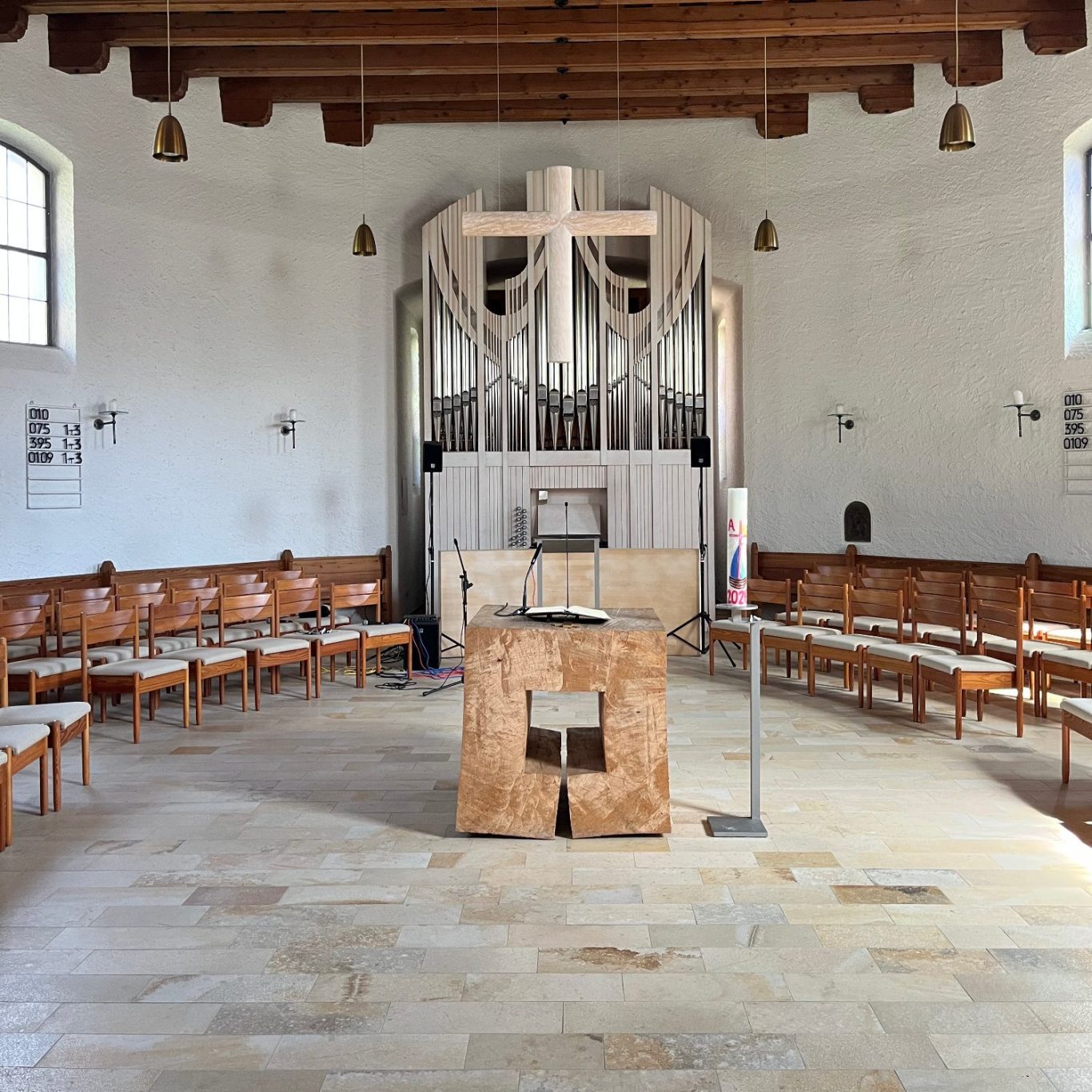 Innenansicht des ovalförmigen Kirchenschiffes der St. Lukas Kirche mit einem Altar aus Holz in der Mitte und der Orgel im Hintergrund